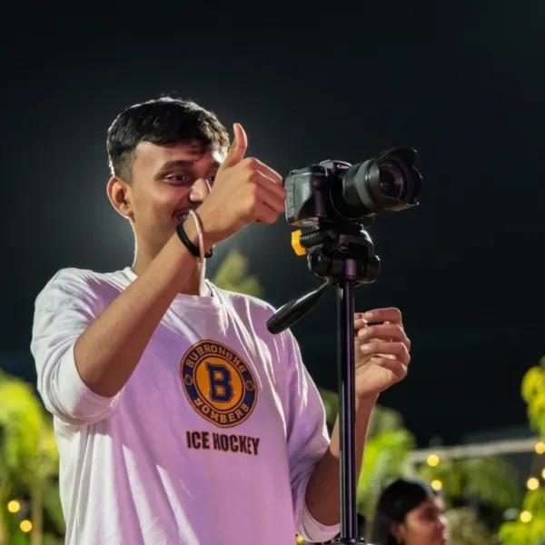 Anshul giving a thumbs-up beside his camera on a tripod