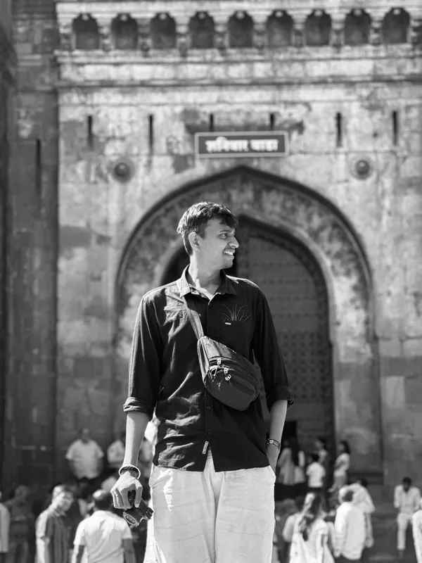 Black and white portrait of Anshul standing outside a historic gateway